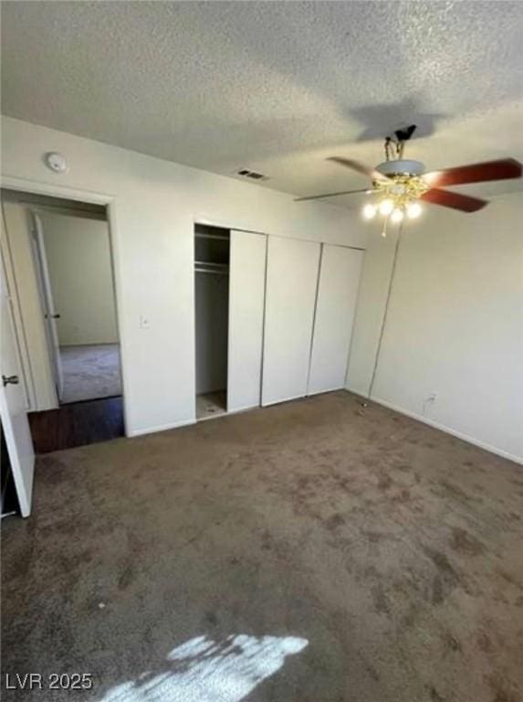 unfurnished bedroom with a textured ceiling, carpet floors, visible vents, and a ceiling fan