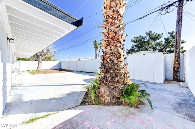 exterior space featuring a patio area, a shed, a fenced backyard, and an outdoor structure