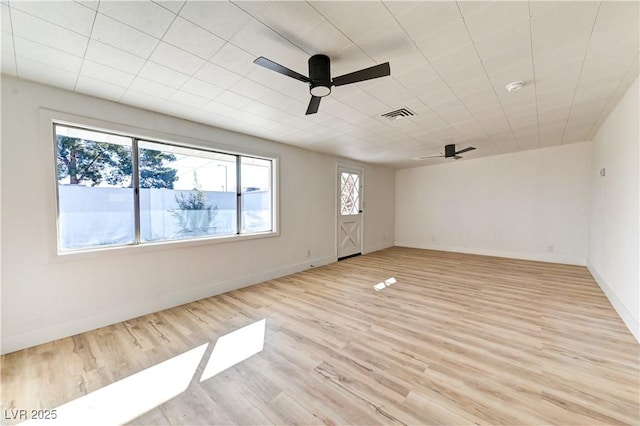 spare room featuring light wood-type flooring, visible vents, ceiling fan, and baseboards