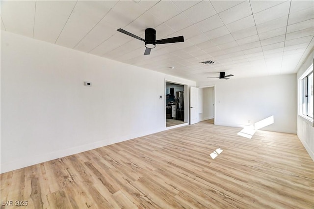 unfurnished room featuring light wood-type flooring, visible vents, ceiling fan, and baseboards