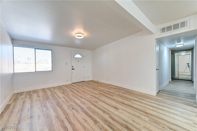 unfurnished room featuring light wood-type flooring, baseboards, and visible vents