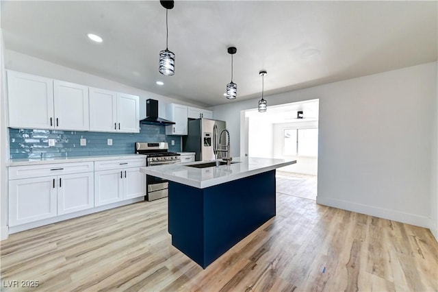 kitchen with white cabinets, appliances with stainless steel finishes, a sink, wall chimney range hood, and backsplash