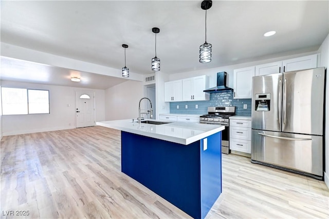 kitchen with decorative backsplash, stainless steel appliances, light countertops, wall chimney range hood, and a sink