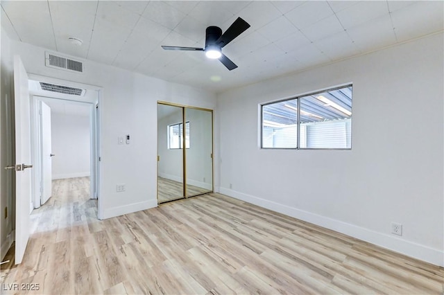 unfurnished bedroom featuring light wood finished floors, a closet, visible vents, and baseboards