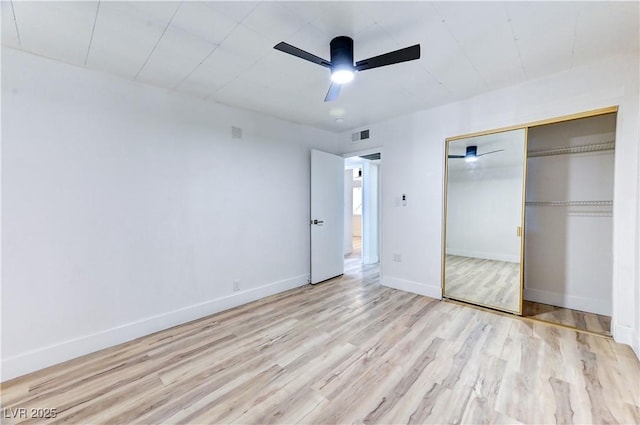 unfurnished bedroom featuring baseboards, visible vents, a ceiling fan, wood finished floors, and a closet