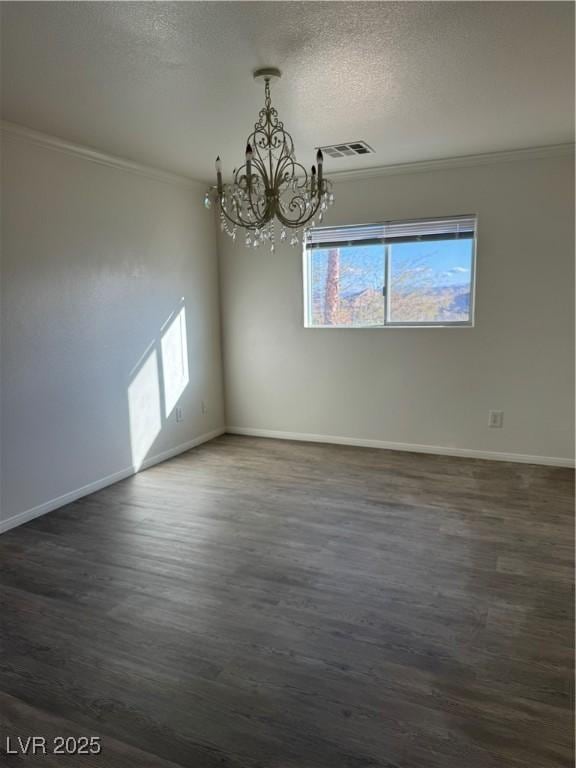 spare room featuring visible vents, dark wood-style flooring, crown molding, a textured ceiling, and a chandelier