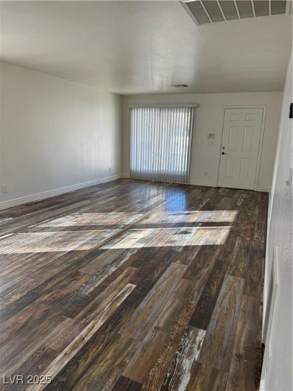 unfurnished room with wood finished floors, visible vents, and baseboards