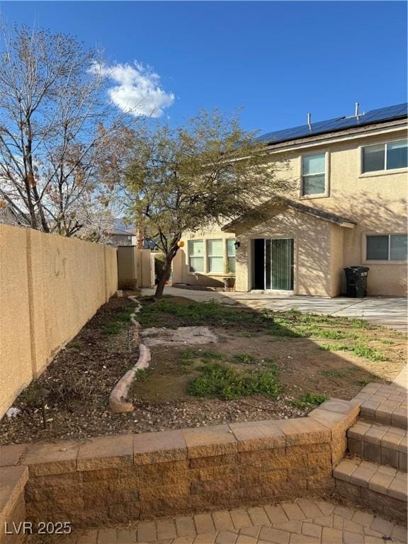 back of house featuring a fenced backyard, a patio, solar panels, and stucco siding