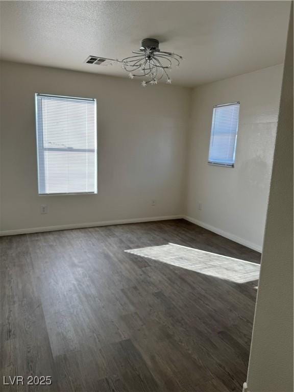 empty room with ceiling fan, visible vents, baseboards, and wood finished floors