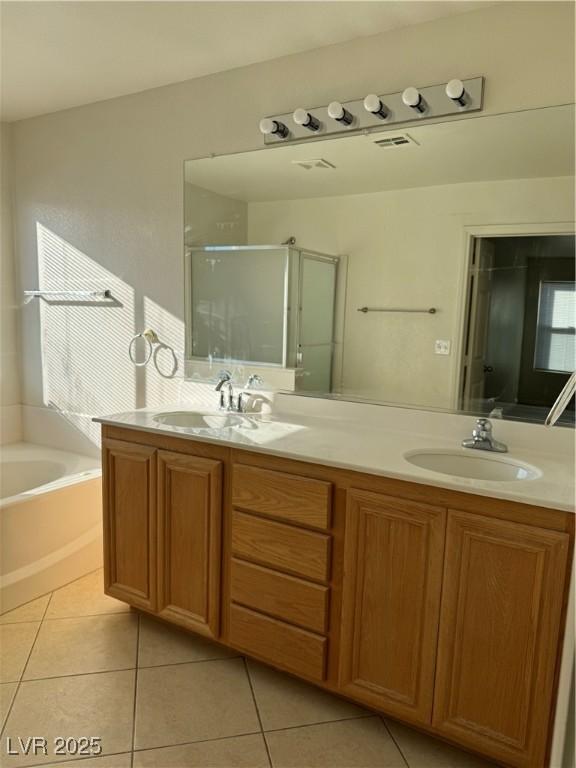 bathroom featuring tile patterned flooring, a sink, a shower stall, and double vanity