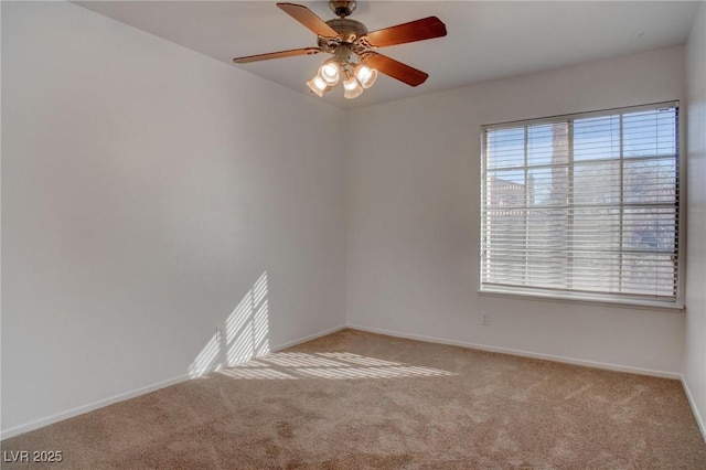 empty room with carpet flooring, a ceiling fan, and baseboards