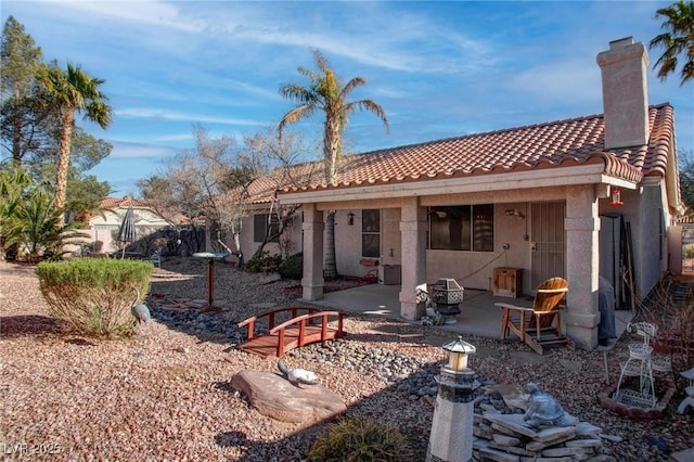 back of property with a chimney, a patio, a tiled roof, and stucco siding