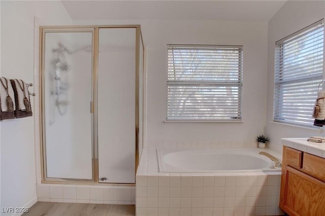 full bathroom featuring a shower stall, wood finished floors, a bath, and vanity