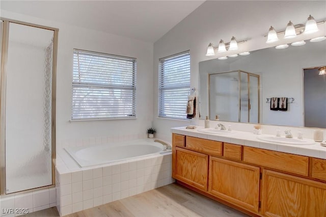 full bathroom featuring a stall shower, a sink, lofted ceiling, and a bath