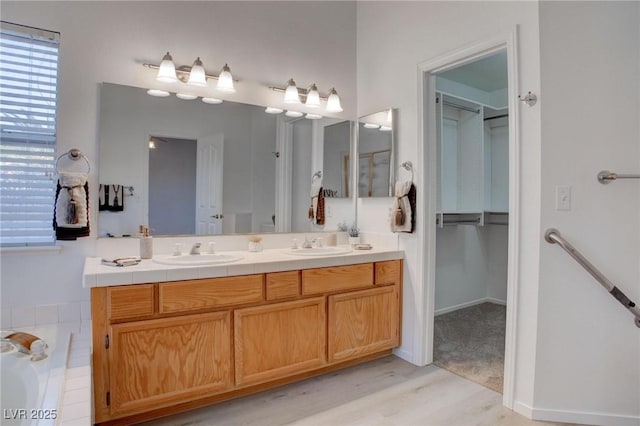 bathroom with a bathtub, a sink, a spacious closet, and double vanity