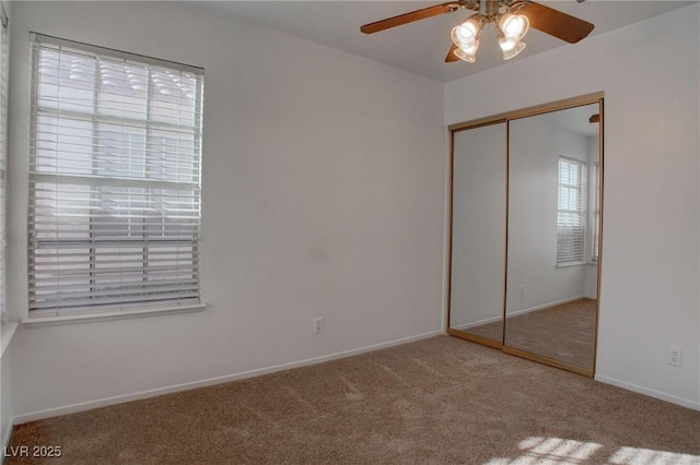 unfurnished bedroom featuring carpet floors, a closet, baseboards, and a ceiling fan