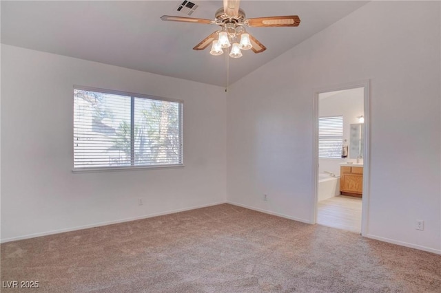 spare room with lofted ceiling, a healthy amount of sunlight, light carpet, and visible vents