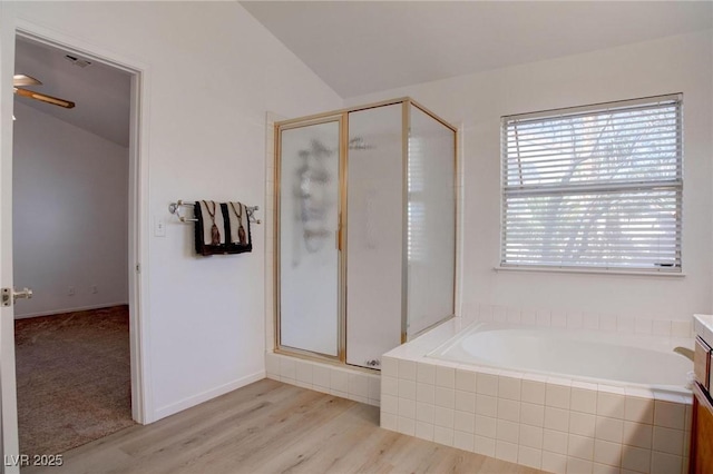 bathroom with a garden tub, lofted ceiling, a shower stall, wood finished floors, and baseboards