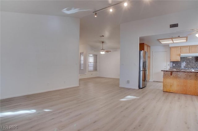 unfurnished living room with ceiling fan, lofted ceiling, visible vents, baseboards, and light wood-style floors