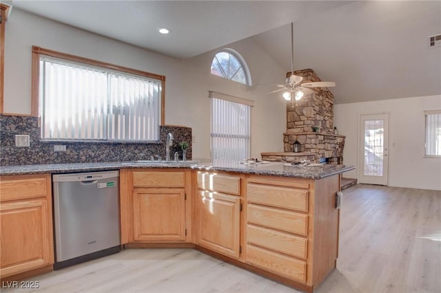 kitchen featuring lofted ceiling, a peninsula, a sink, stainless steel dishwasher, and light wood-type flooring