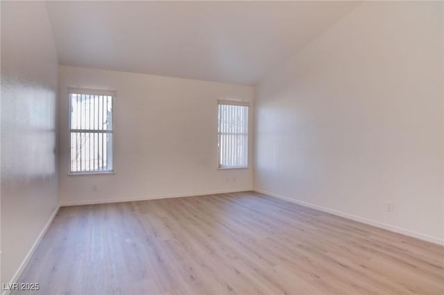 spare room featuring baseboards, vaulted ceiling, and wood finished floors