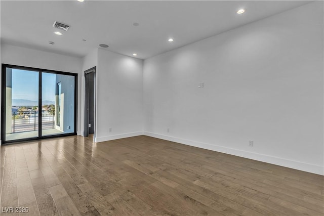 unfurnished room with baseboards, visible vents, wood finished floors, and recessed lighting