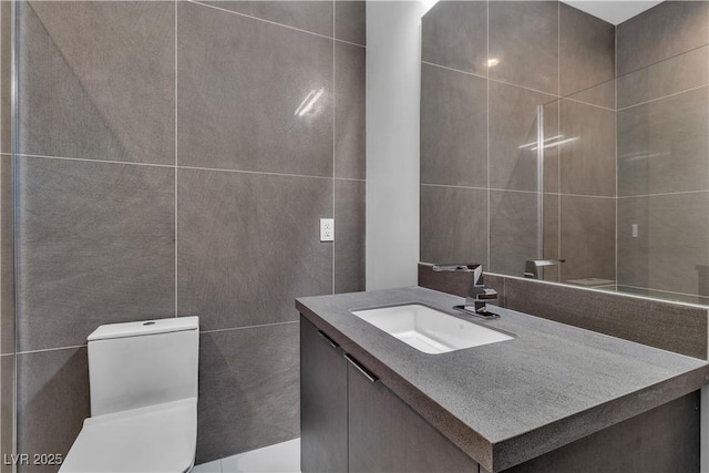 bathroom with toilet, tile walls, and vanity