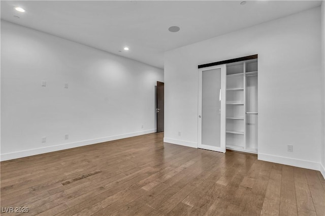 unfurnished bedroom with baseboards, wood finished floors, and recessed lighting