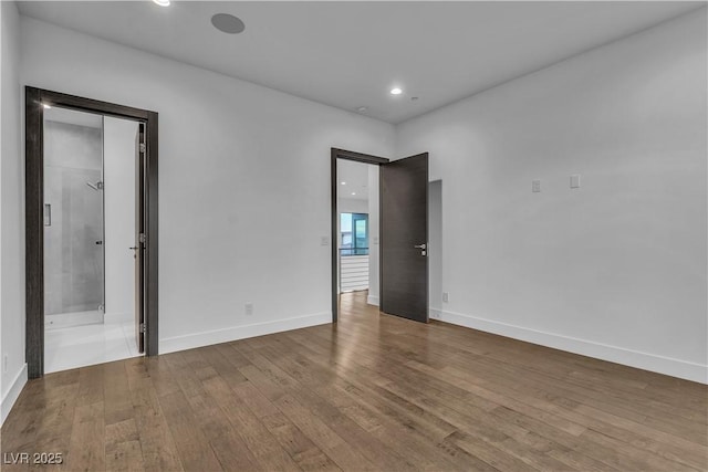 unfurnished bedroom featuring recessed lighting, baseboards, ensuite bath, and hardwood / wood-style floors