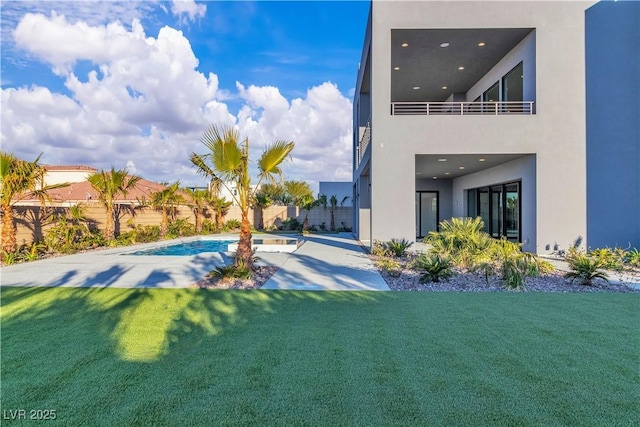 rear view of house with a fenced in pool, a lawn, a patio, and stucco siding