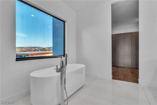 bathroom featuring a freestanding tub, baseboards, and tile patterned floors