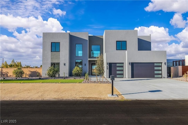 contemporary home featuring driveway, an attached garage, and stucco siding