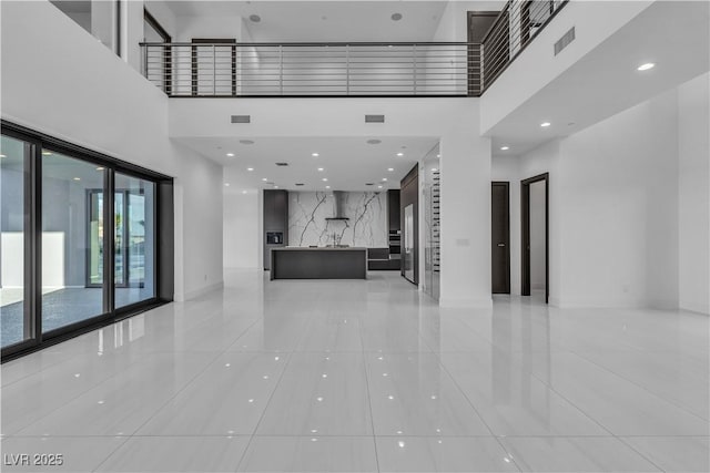 unfurnished living room with a towering ceiling and visible vents