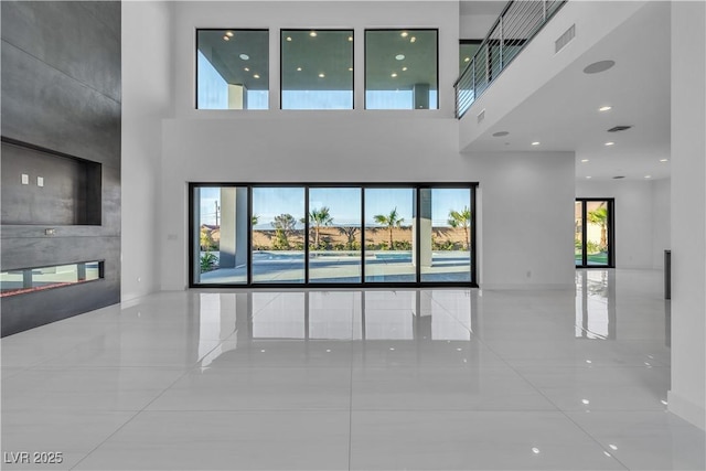 unfurnished living room featuring visible vents and a towering ceiling