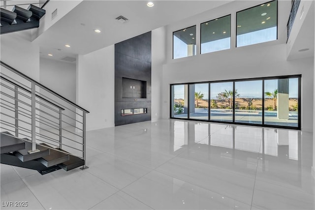 living room featuring stairs, a towering ceiling, visible vents, and recessed lighting