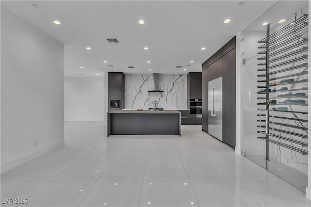 interior space with wall chimney range hood, modern cabinets, visible vents, and recessed lighting