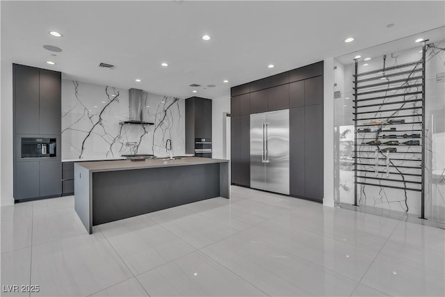 kitchen featuring recessed lighting, a sink, light countertops, wall chimney range hood, and modern cabinets