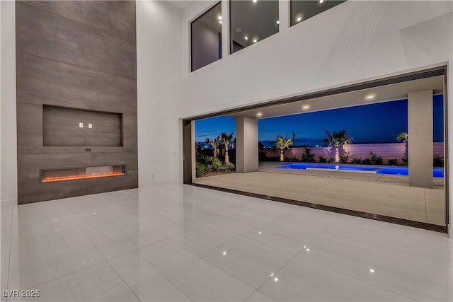 unfurnished living room with a fireplace, a high ceiling, and tile patterned floors