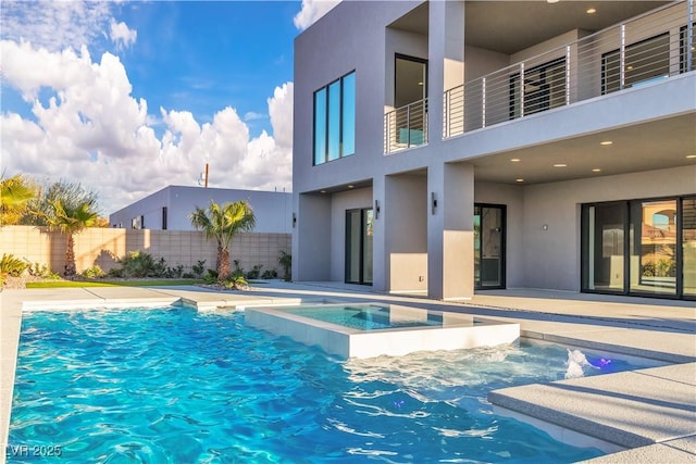 view of pool with a pool with connected hot tub, fence, and a patio