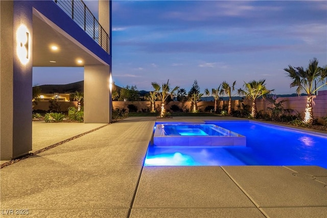 view of swimming pool featuring a fenced backyard, a pool with connected hot tub, and a patio