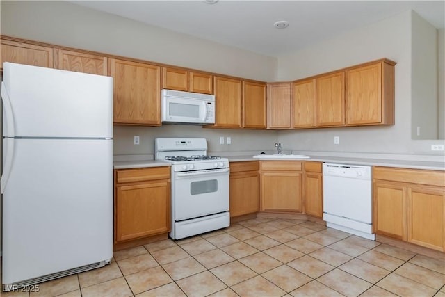 kitchen featuring light brown cabinets, light countertops, white appliances, and a sink