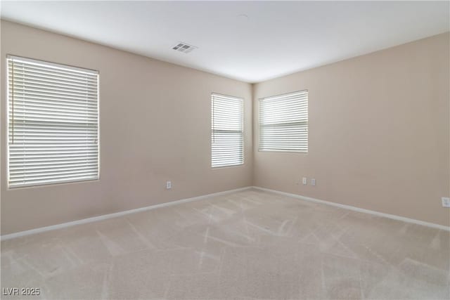 unfurnished room with baseboards, visible vents, and light colored carpet