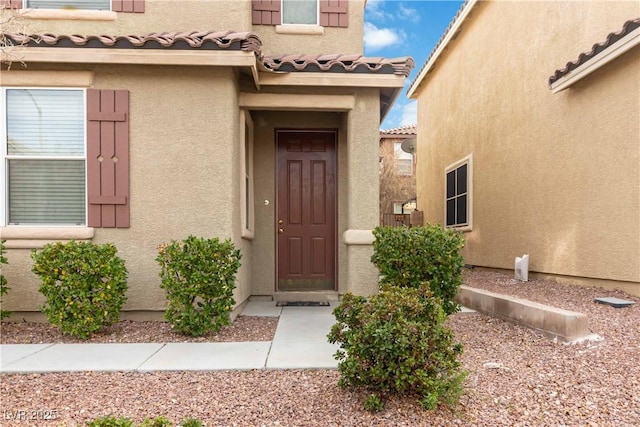 doorway to property with a tiled roof and stucco siding