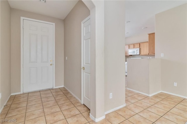 entryway with light tile patterned floors, arched walkways, and baseboards