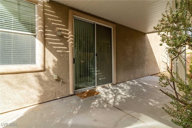 property entrance with a patio area and stucco siding