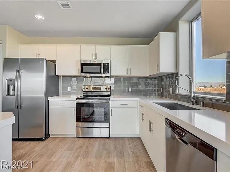 kitchen with visible vents, light wood-style flooring, stainless steel appliances, light countertops, and a sink