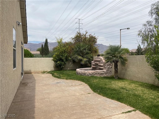 view of yard featuring a patio area, a fenced backyard, and a mountain view