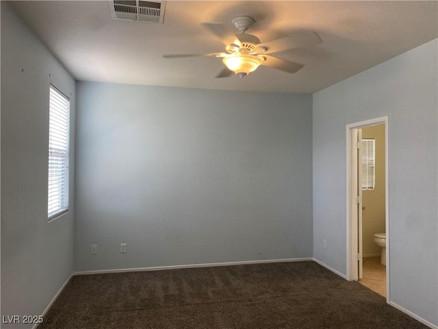 carpeted empty room with a ceiling fan, visible vents, and baseboards