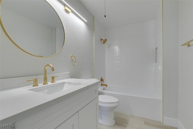 bathroom featuring a textured wall, toilet, wood finished floors, vanity, and  shower combination