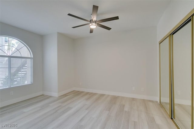 unfurnished bedroom featuring ceiling fan, a closet, light wood-style flooring, and baseboards